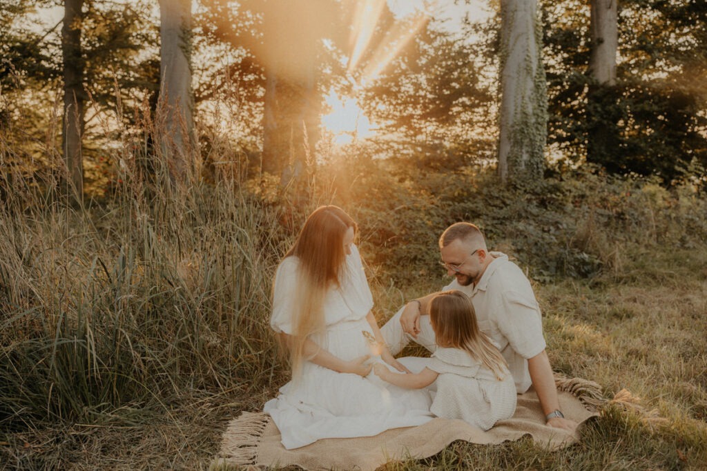 Familienfotografie Mama Papa Kind im Sonnenuntergang am Waldrand